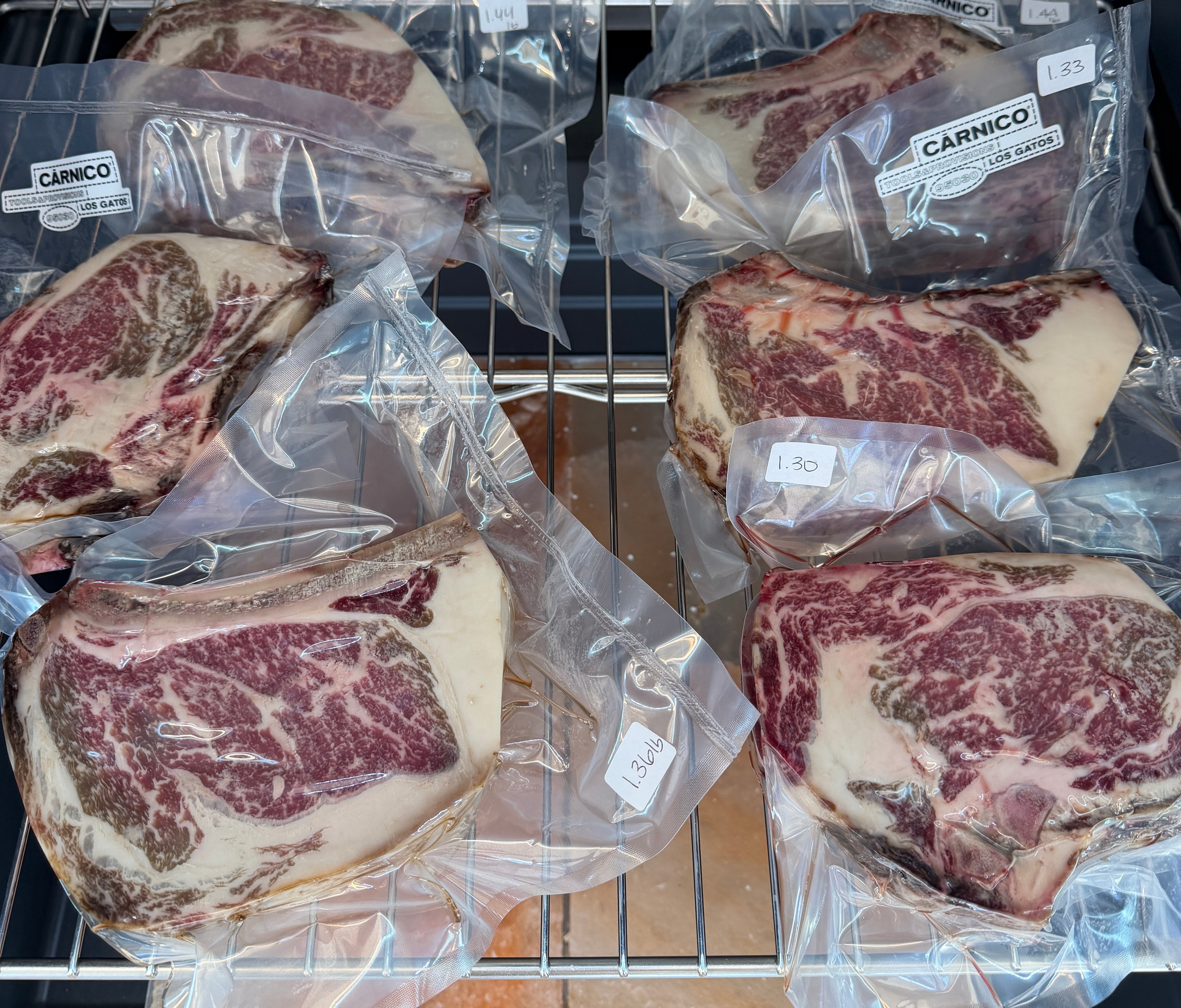 Packaged steaks on a metal rack with a kitchen background